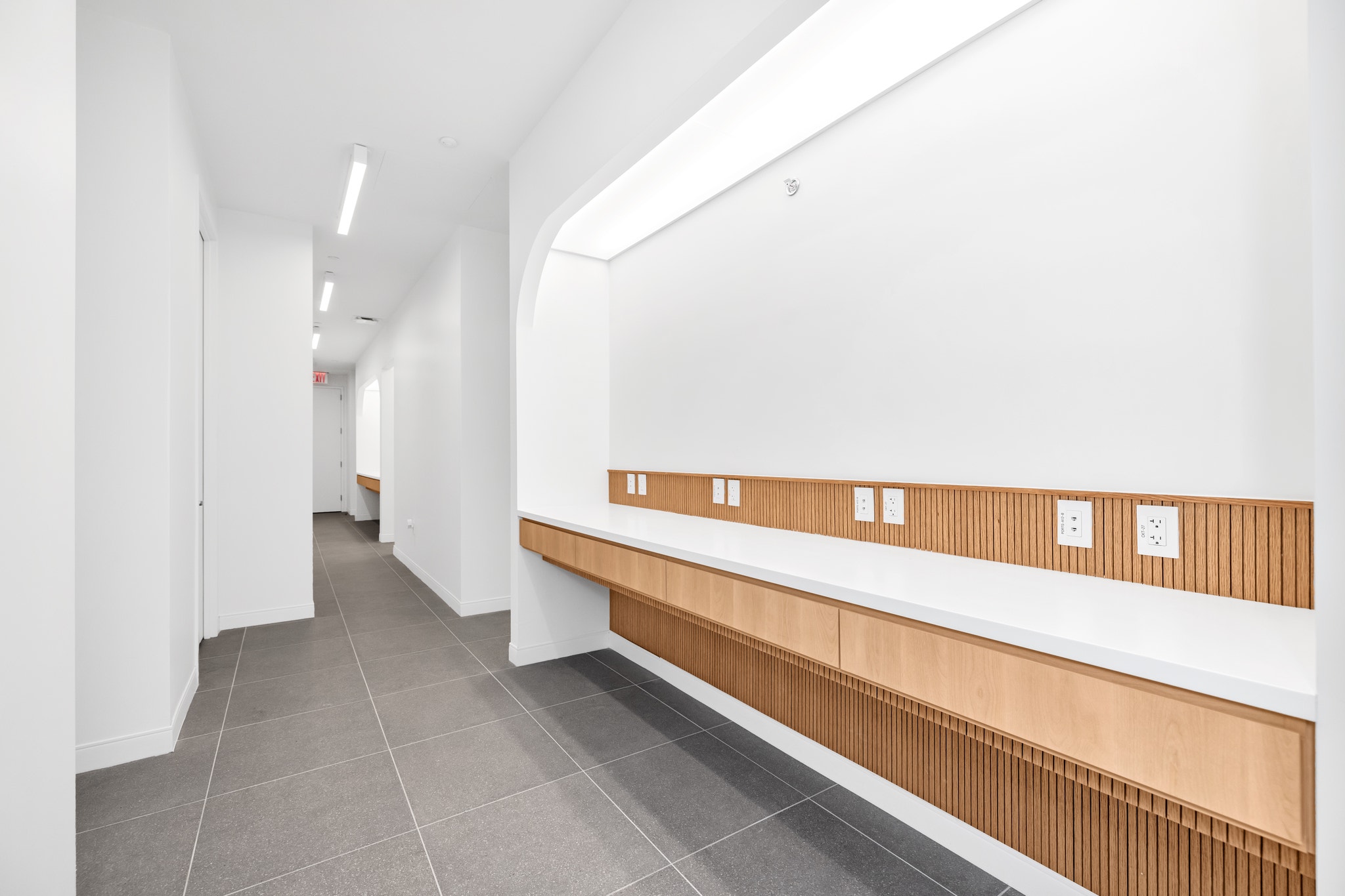 White commercial hallway with built-in wood bench and recessed lighting