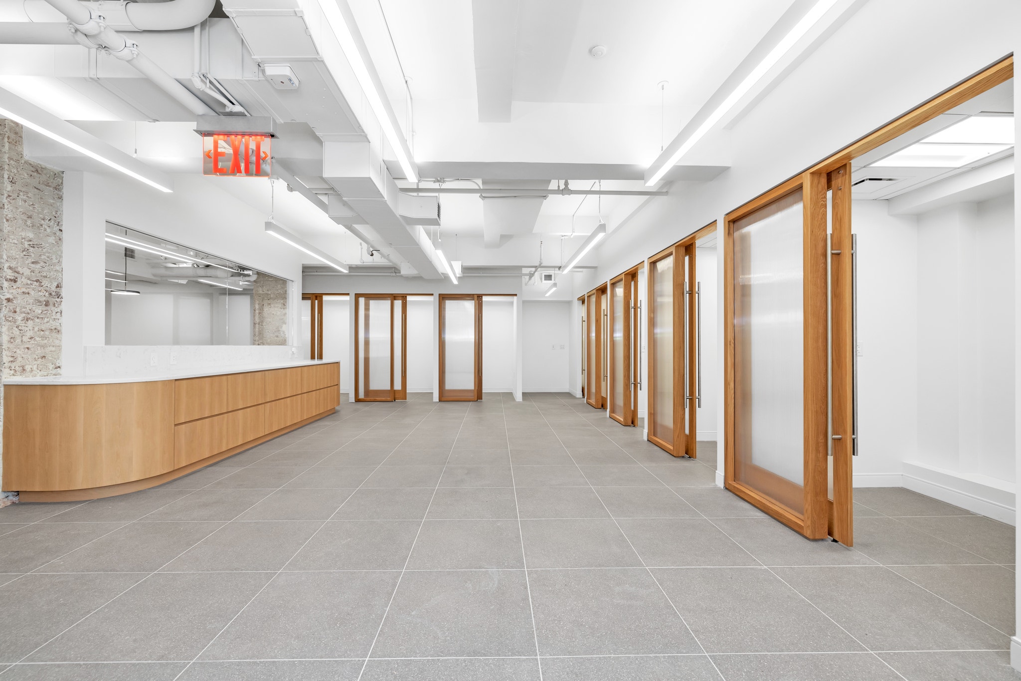 Open commercial floor plan with wood-framed glass partition doors and exposed ceiling