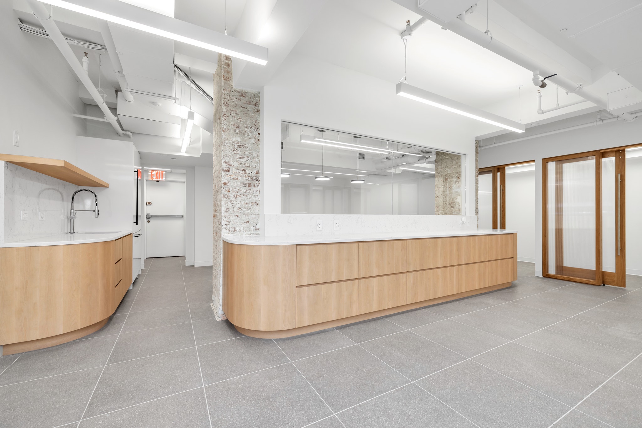 Office lobby with curved wood reception desk, exposed ceiling, and structural column