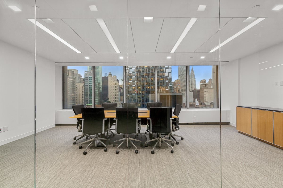 Glass conference room with black leather chairs and sweeping Manhattan skyline views