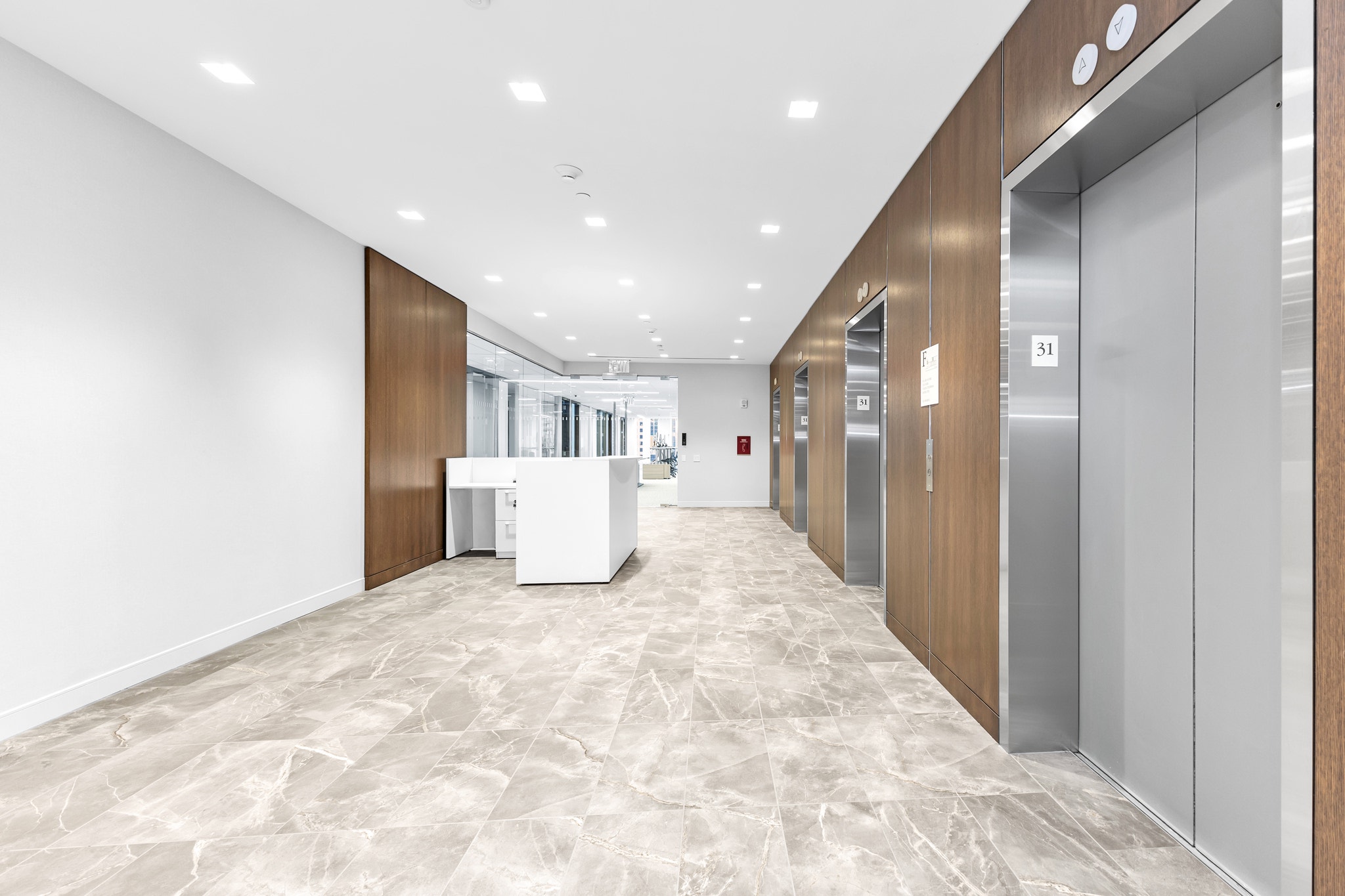 Elevator lobby with walnut wood paneling, stainless doors, and marble tile flooring on floor 31