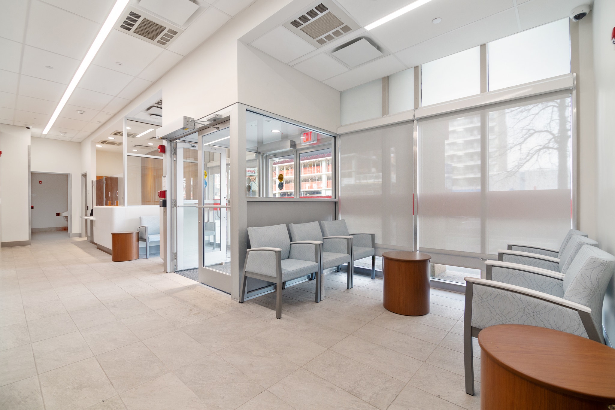 Clinic waiting area with light blue chairs, glass entry vestibule, and frosted window walls