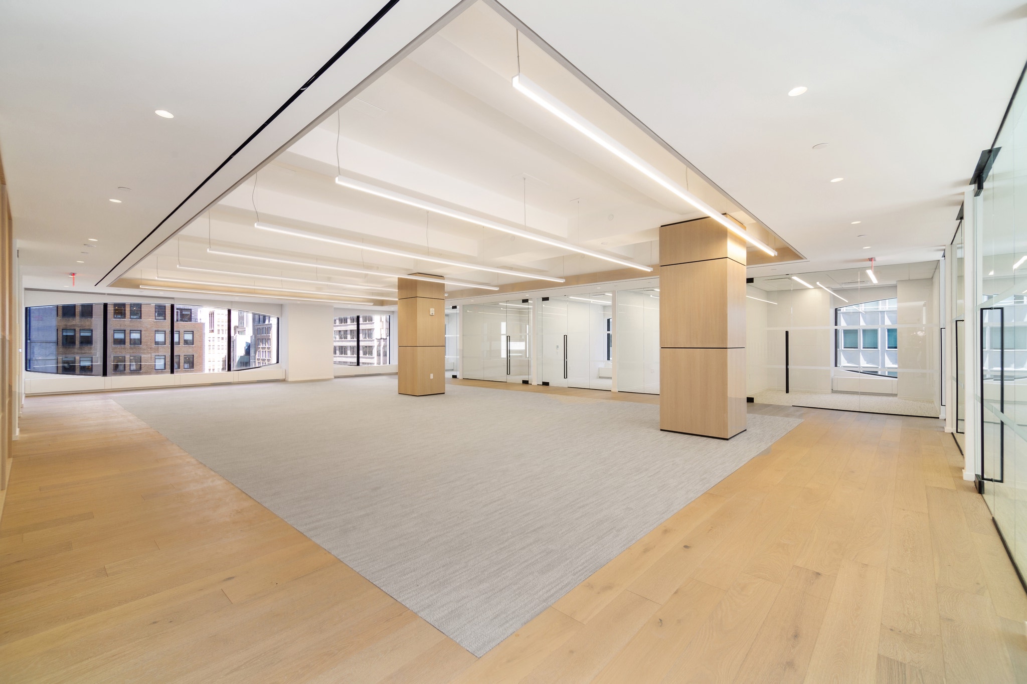 Wood-clad structural columns anchor an open office floor with glass rooms and city views